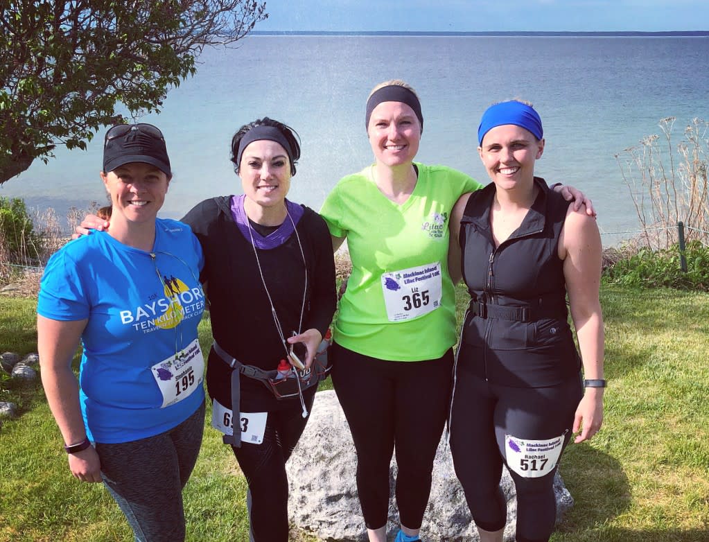 Four women pose along the lakeshore after running in the Mackinac Island Lilac Festival 10K race