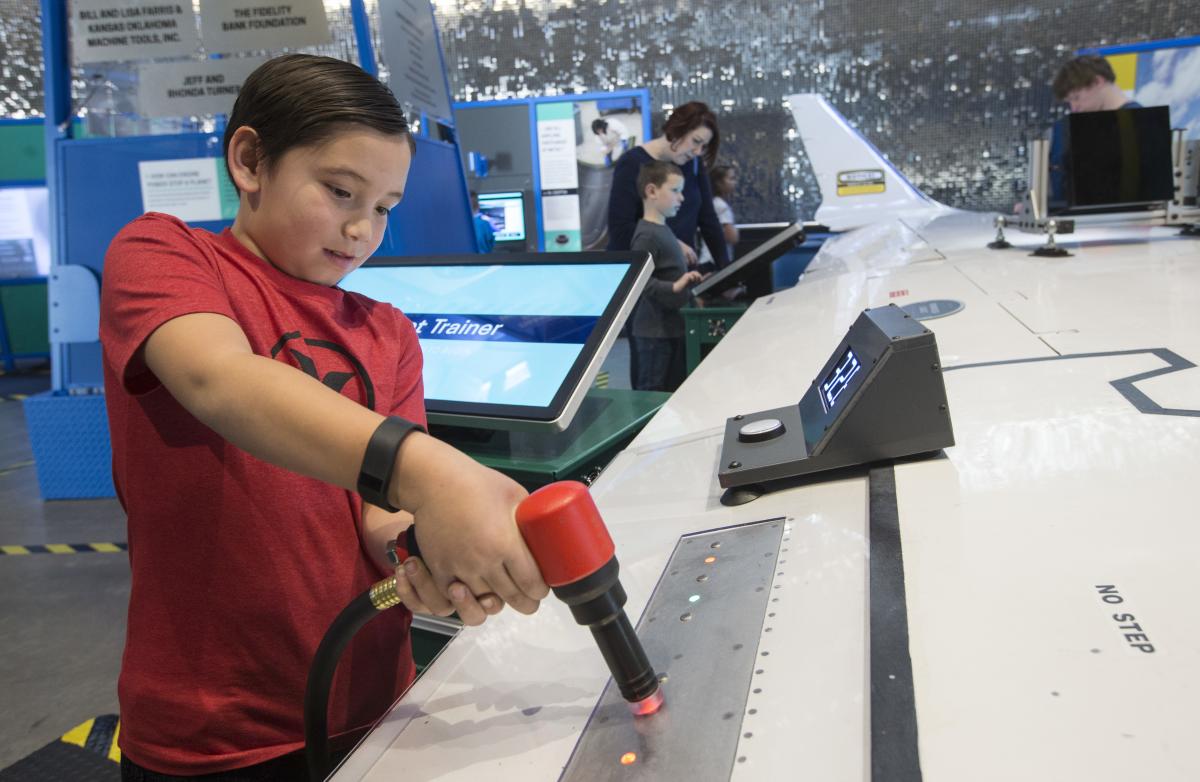 A young boy works on an aircraft wing at an interactive exhibit at Exploration Place