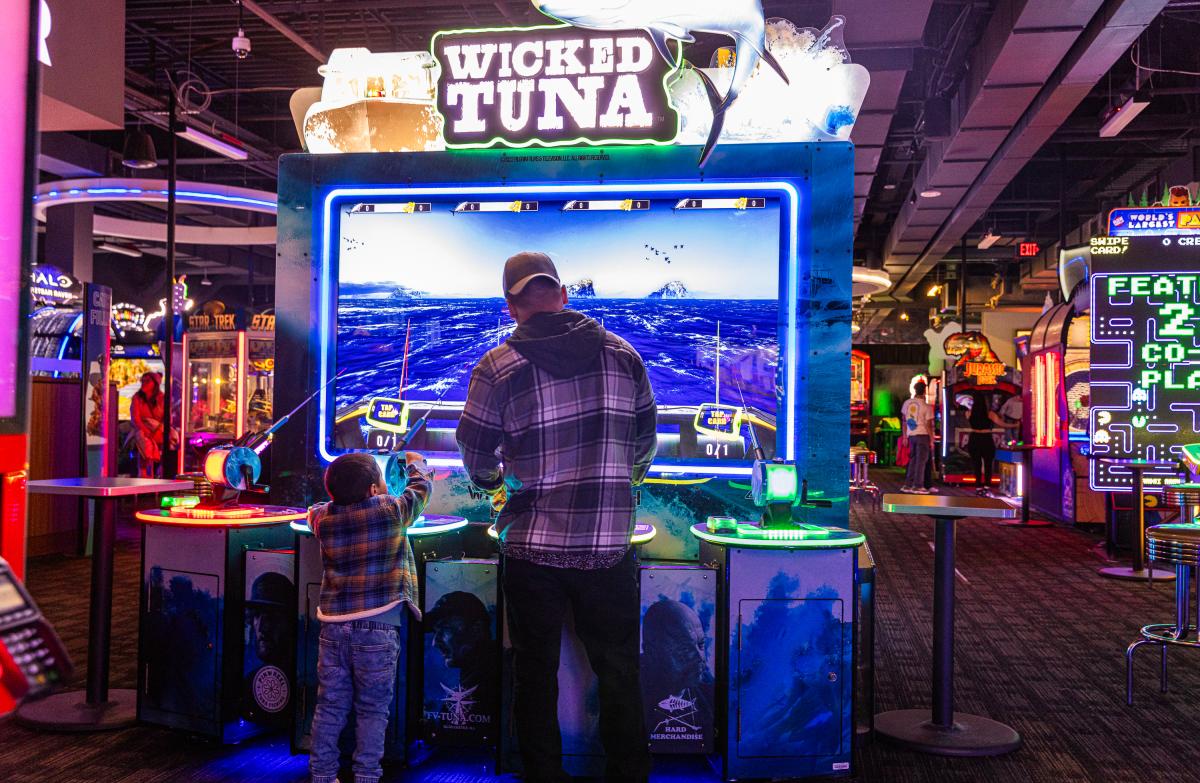 Son and father playing a game at an arcade