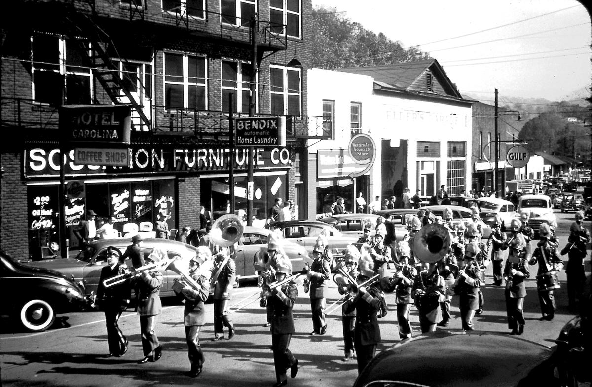 1950 homecoming marching band parading past the Hotel Carolina, Sossamon Furniture Co. and Western Auto on the east end of Main Street in Sylva, NC