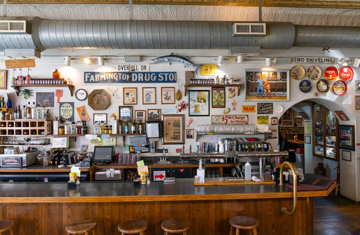 Interior of the Three Rivers Brewery featuring a bar counter, various vintage signs and posters on the walls.