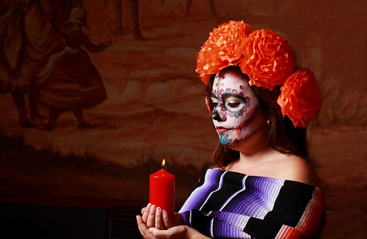 Woman holding a candle in Day of the Dead makeup