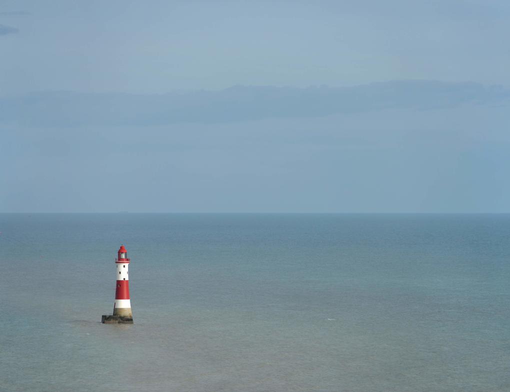 Red and white striped lighthouse in the sea at Beachy Head, Sussex