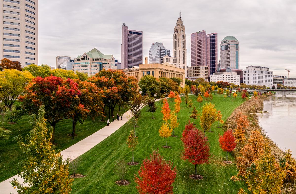 Trees in fall colors on riverfront of Scioto Mile with city skyline in background