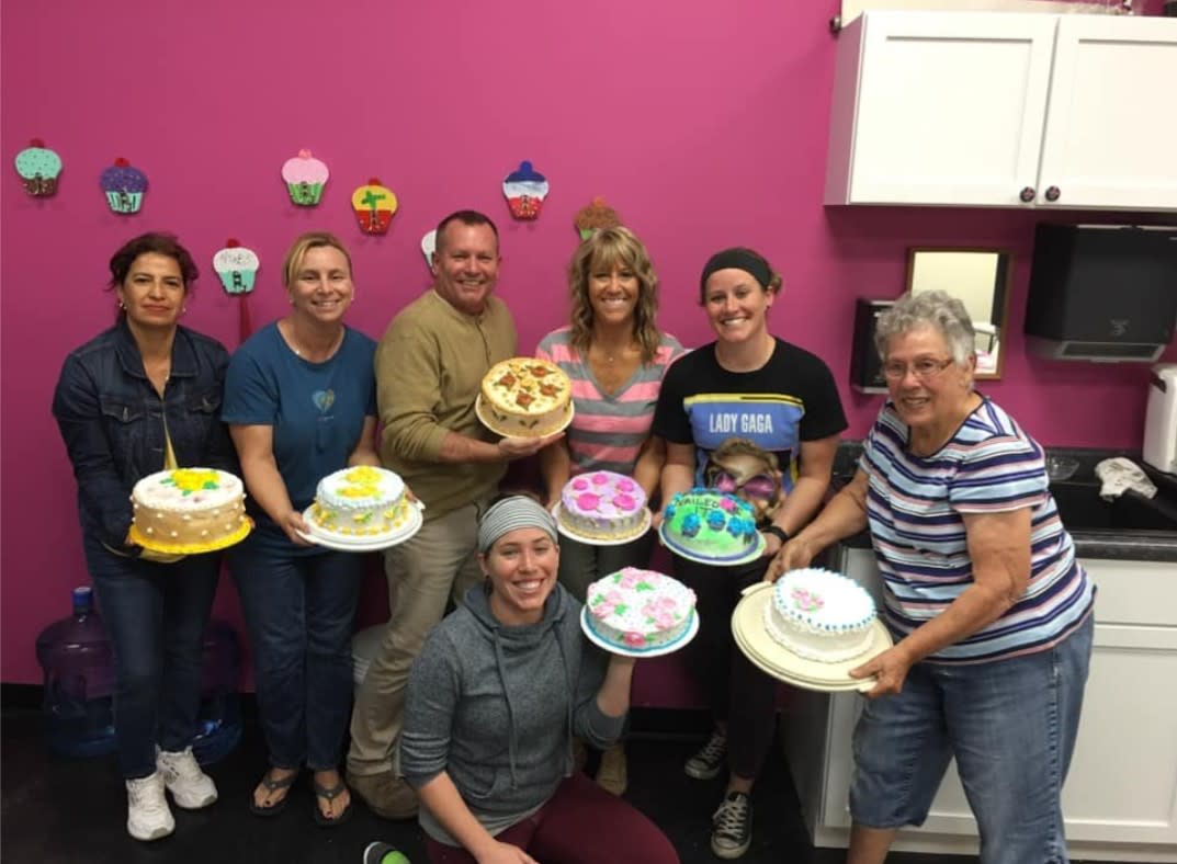 Women and a man pose with their decorated cakes following a class at Cake Stuff in Wichita, KS