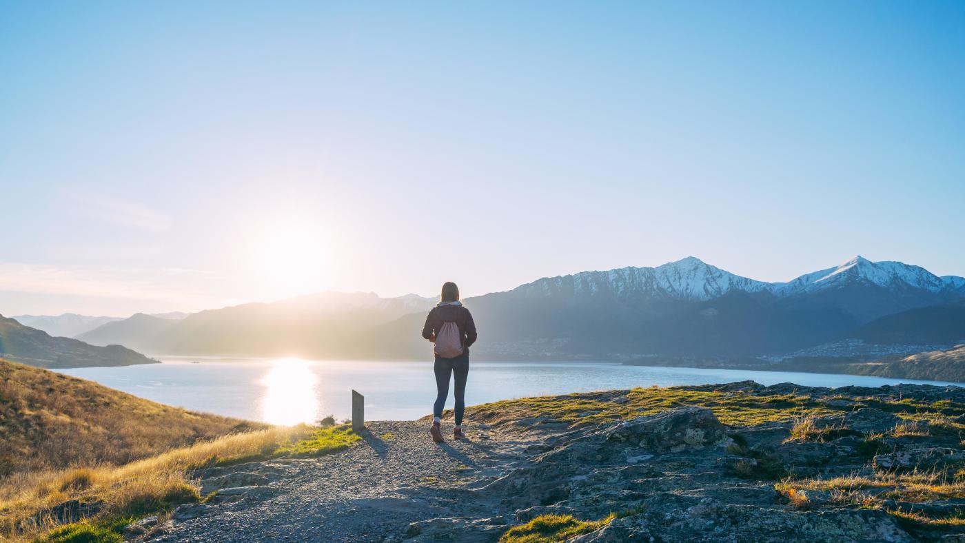 Person on trail at sunset with lake and mountain views