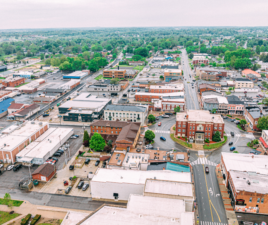An aerial view of downtown Elizabethtown, KY, showcasing the layout of streets, buildings, and greenery, under an overcast sky.