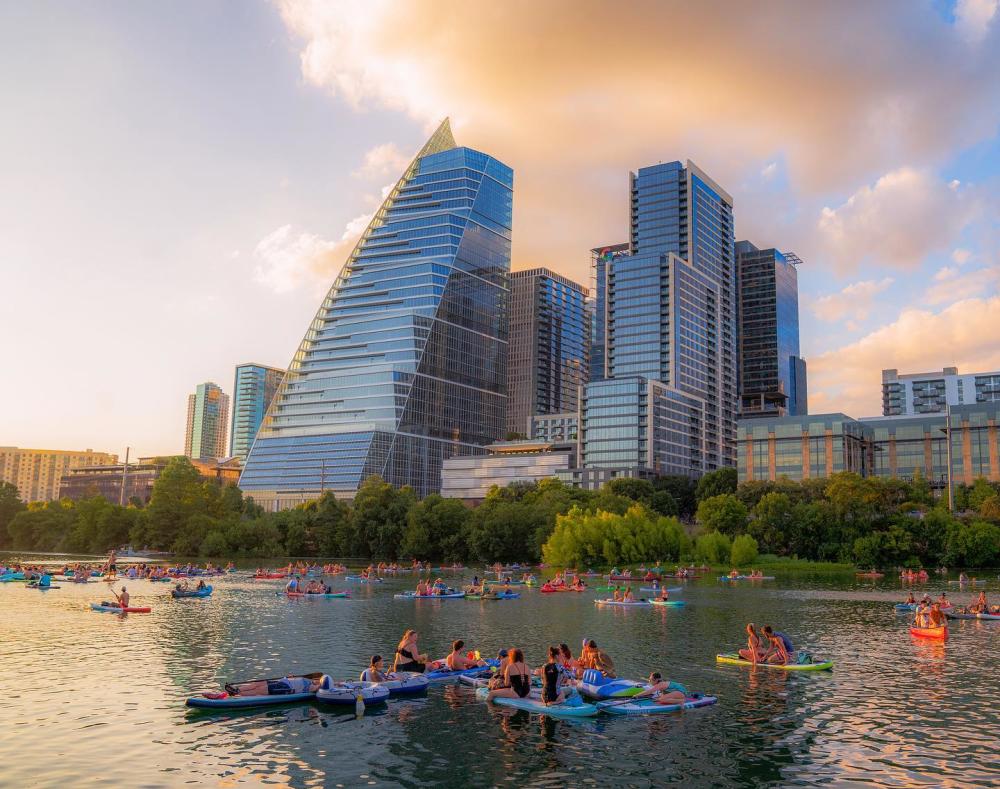 Image of people kayaking on Lady Bird Lake with the downtown skyline in the background.