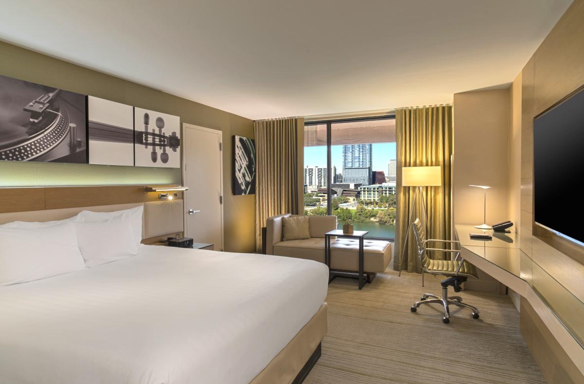 Image of the inside of a hotel hotel room with a bed, lounge chaise and desk at the Hyatt Regency Austin.