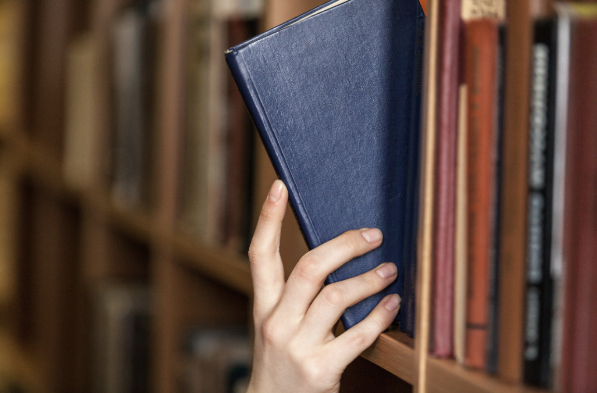 A person putting a library book back on the shelf