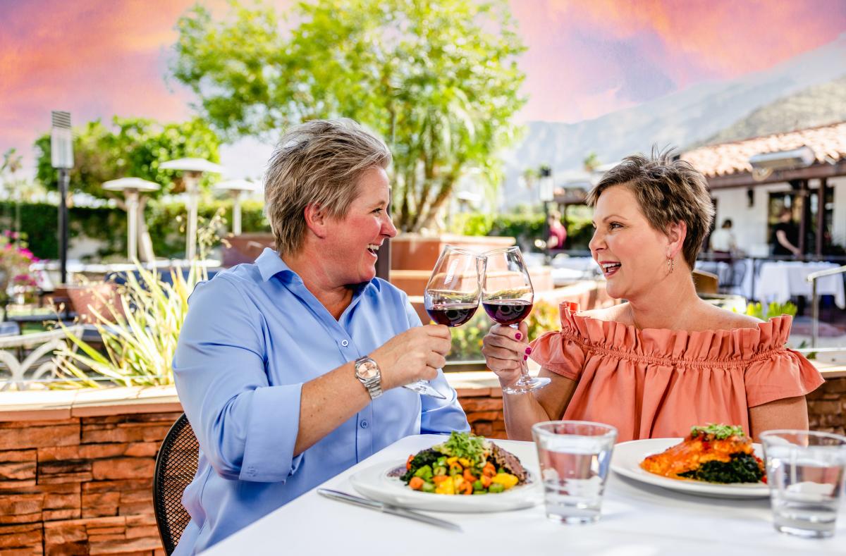 ladies dining wine glasses pink sunset outdoor patio lush scenery