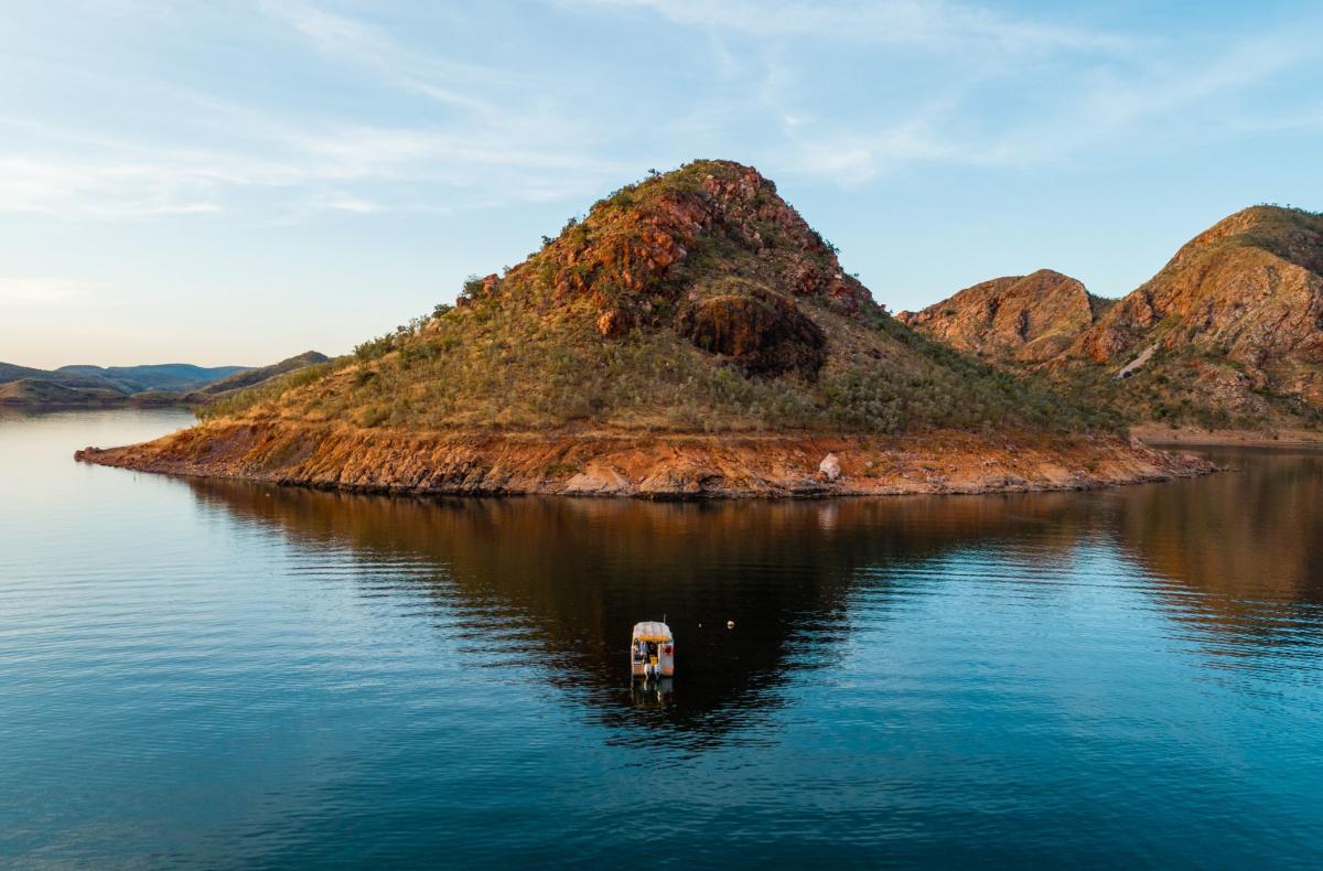 A Lake Argyle Cruises boat shown on the lake in front of one of the lake's islands