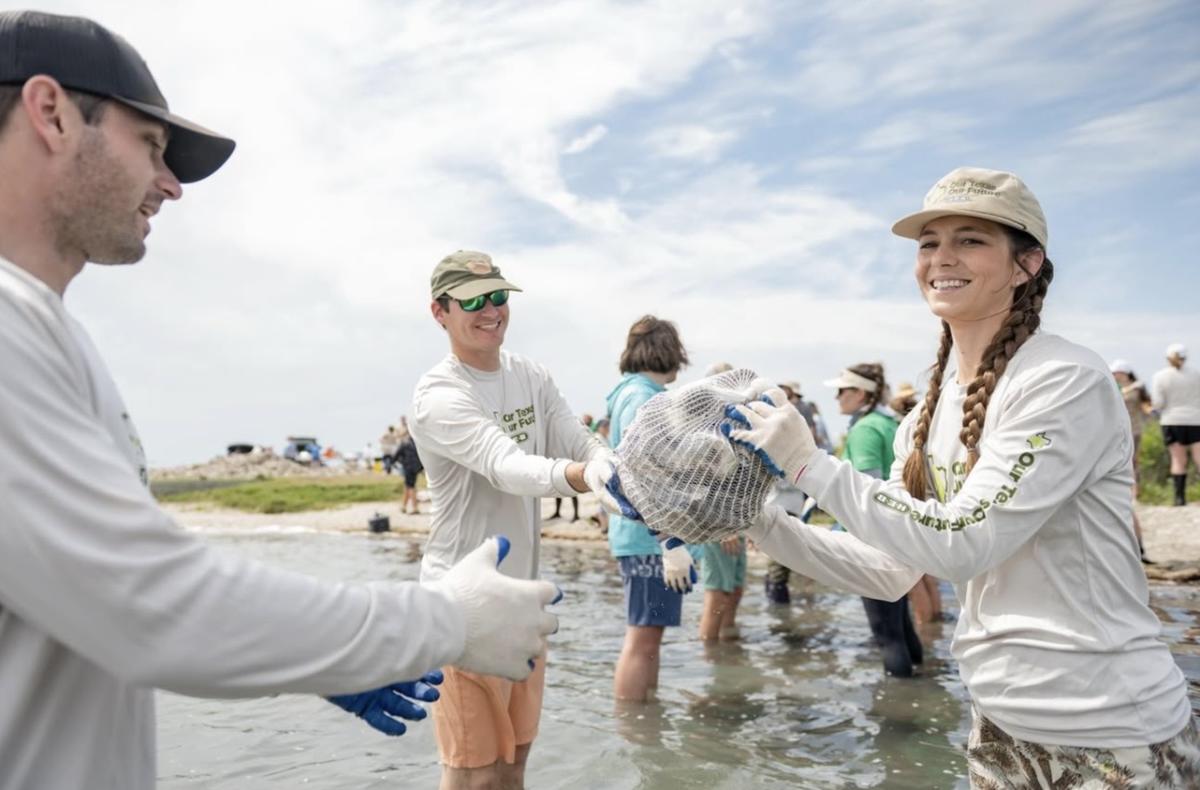 A group of people passing bags of oyster shells down a line.