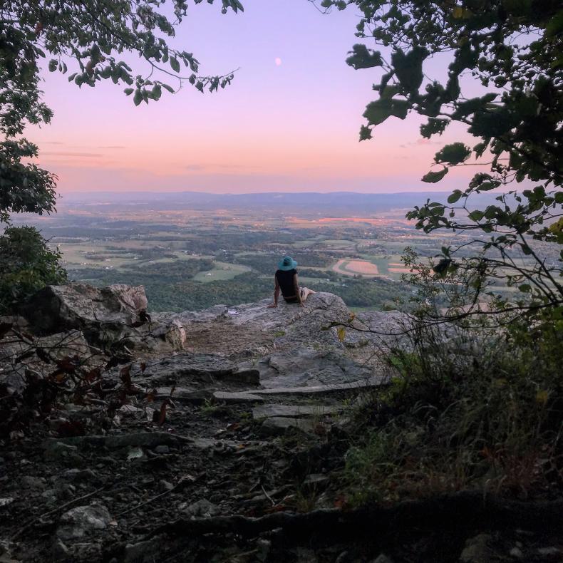 Hiker sitting on rock overlooking valley on Flat Rock Trail