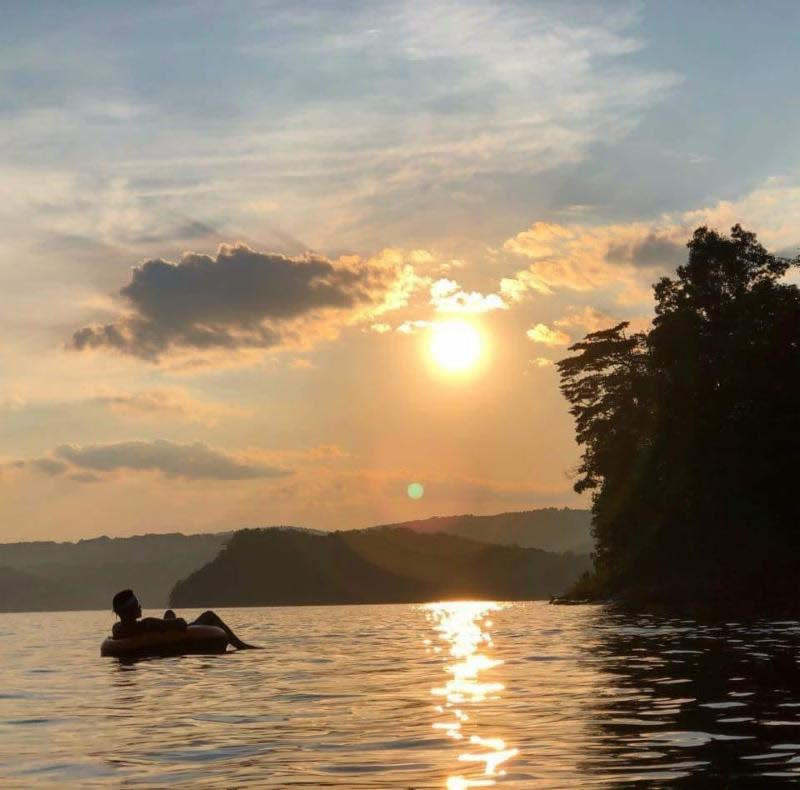 A man inner-tubing on Raystown Lake near sunset