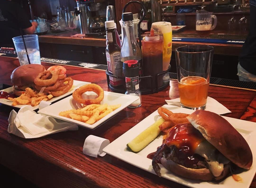 Plates of burgers and glasses of beer sit on the counter of a downtown Mackinac Island bar