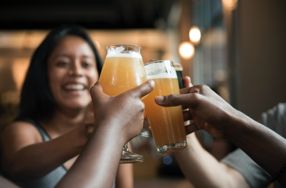 A group of people holding up a few beers.