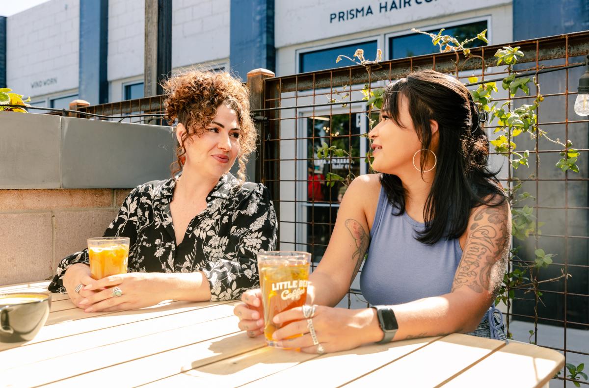 Two women sit and drink coffee on the Little Bear Nob Hill patio