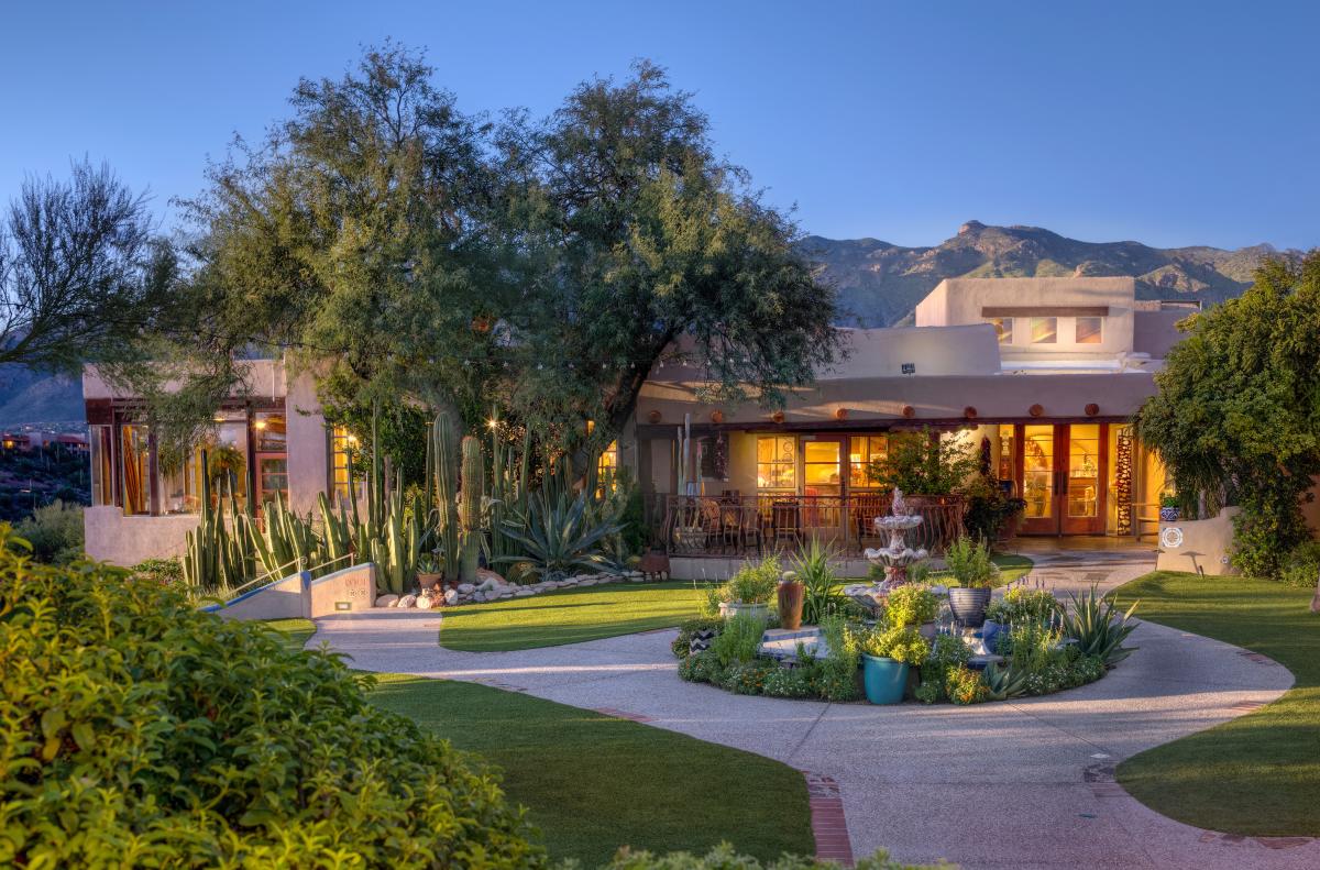 exterior of a brown southwest-style building with cacti, desert plants, and other greenery surrounding it