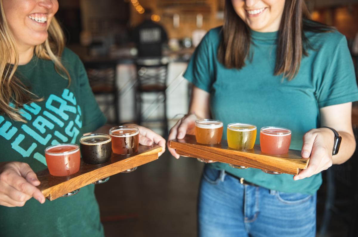 Two women carrying beer flights at Modicum