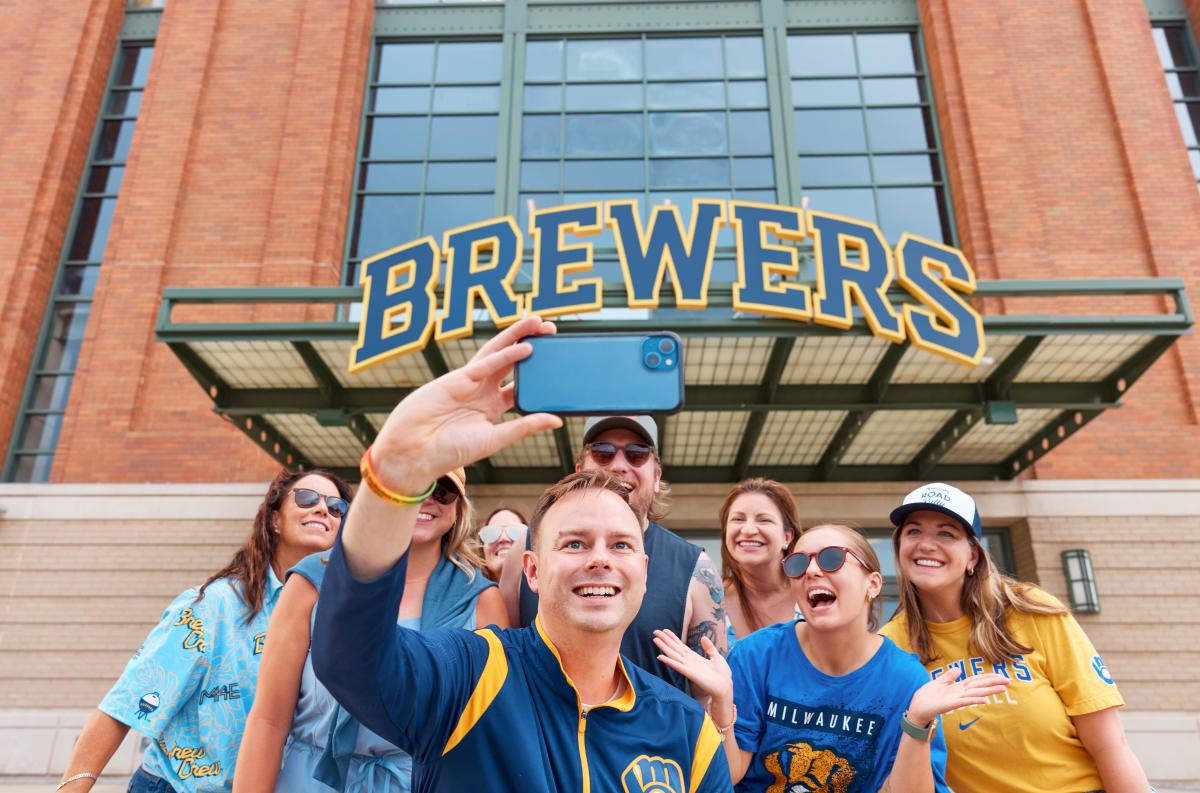 A group of Brewers fans smile in front of American Family Field
