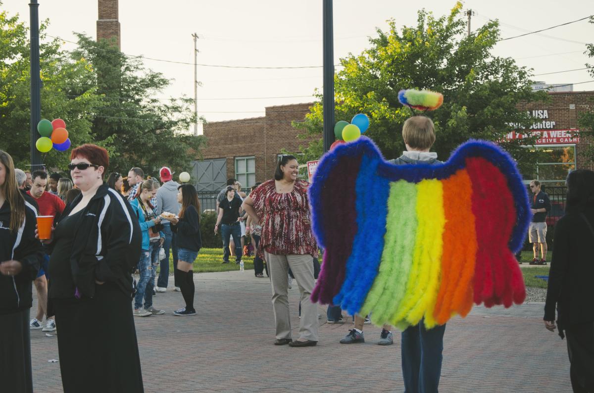 A person wearing colorful wings and a halo at a gathering