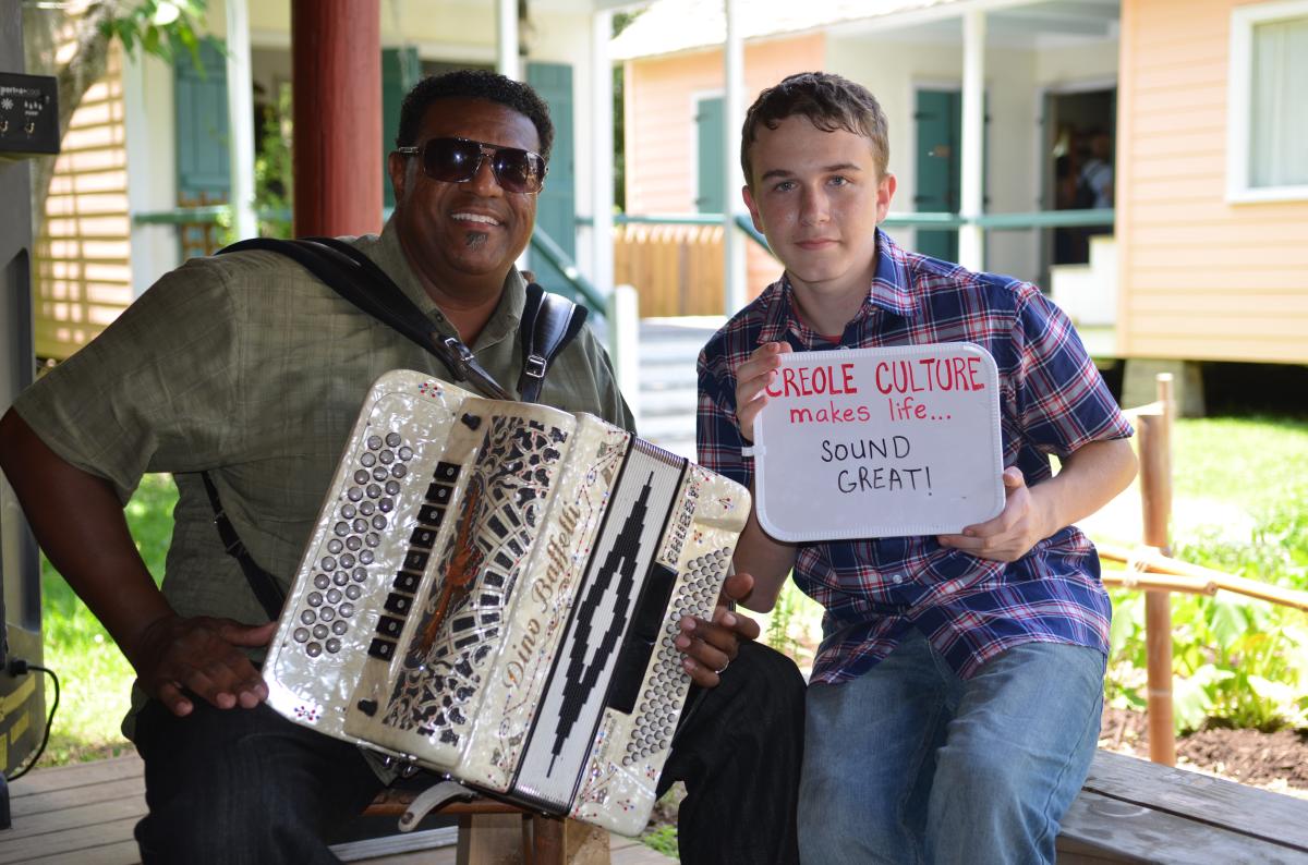 One guy holding an accordion and one guy holding a sign.