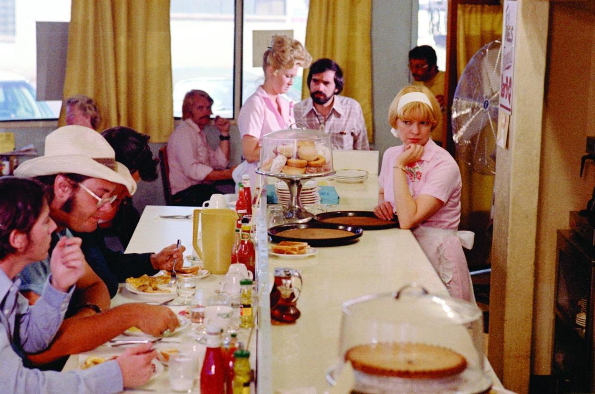 people eating at an old-school diner. Waitress in pink dresses and white apron serve customers