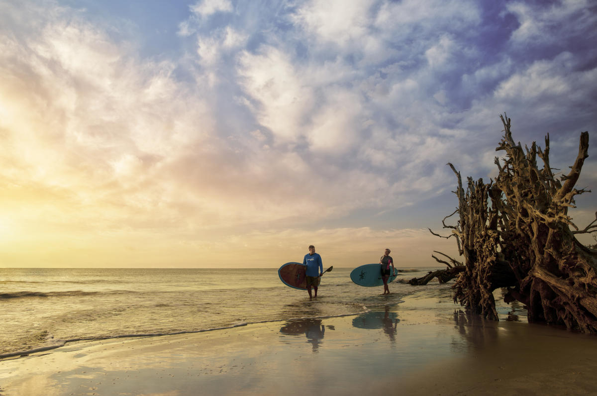 Paddleboarders enjoy a sunrise stroll along Driftwood Beach on Jekyll Island, GA