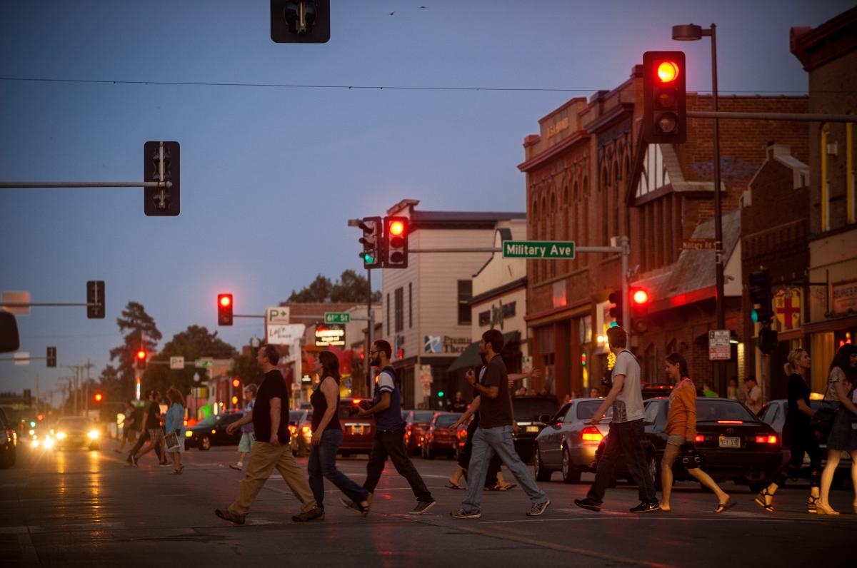 A group of people crossing the street in the Benson neighborhood at night.
