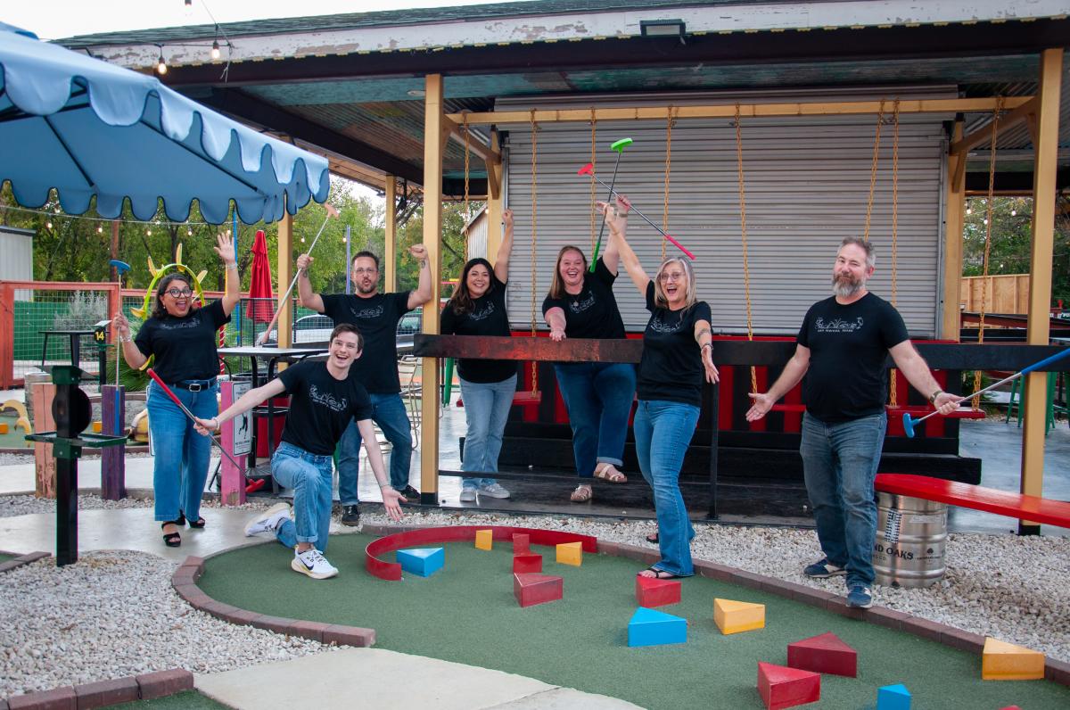 The Visit San Marcos team pose after a rousing game of Putt Putt golf at Putt Pub in Downtown San Marcos, Texas