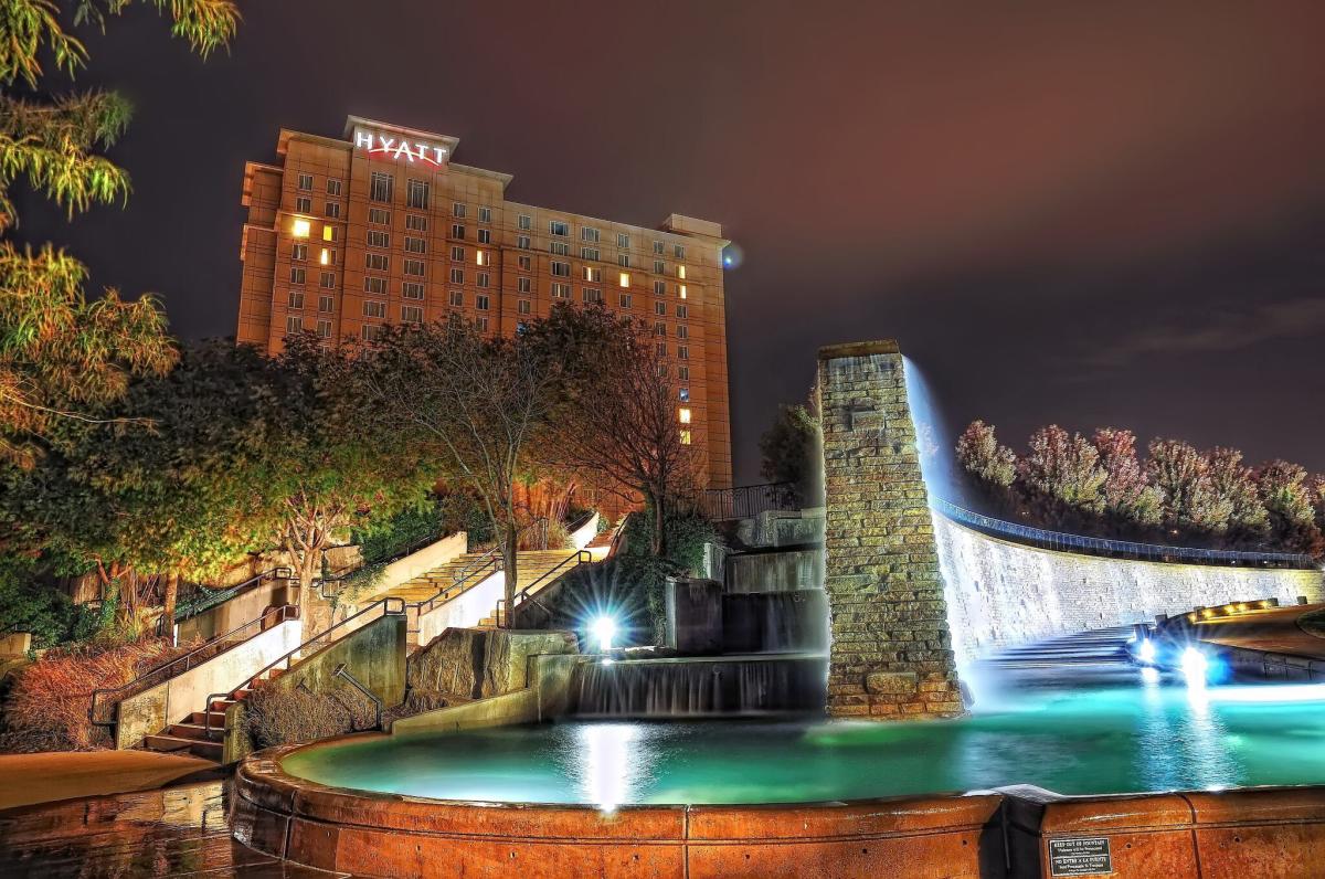 A shot of the water wall fountain and stairs at night with the Hyatt Regency hotel in the background