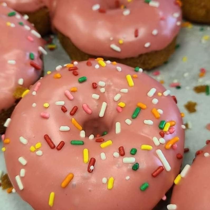 Image is of strawberry iced, cake doughnuts with colored sprinkles on them.