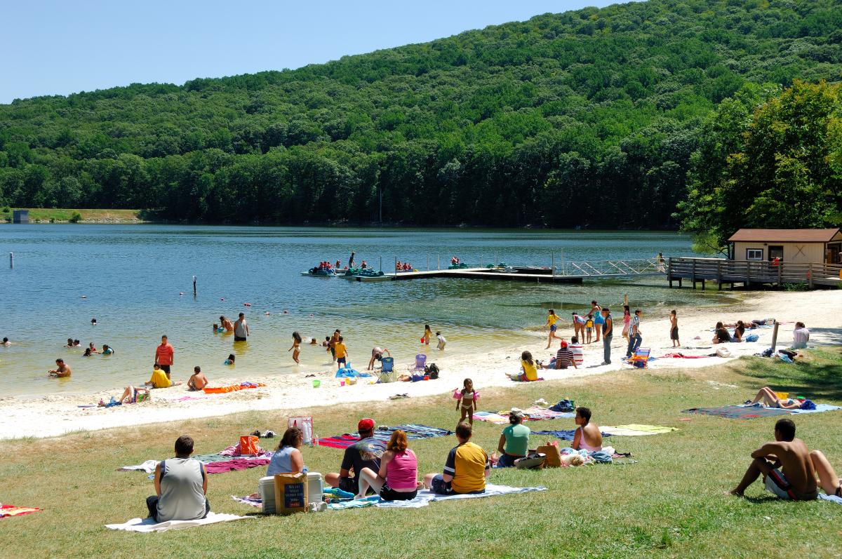 Visitors relax on the beach and enjoy swimming in the lake.
