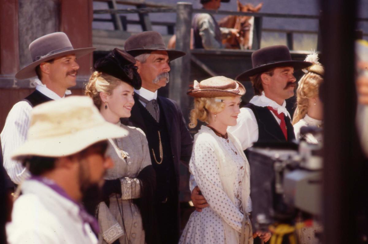 A group of men and women dressed in old-west clothes smiling
