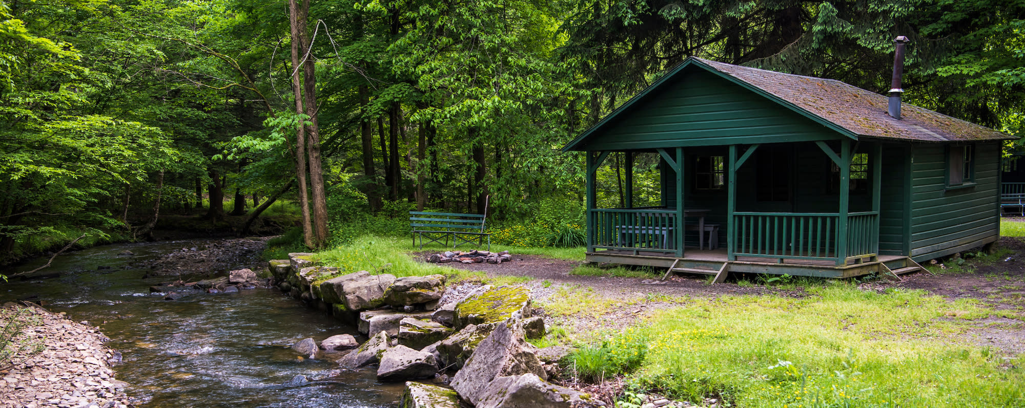 A photo of the exterior of a green cabin at Allegheny State Park