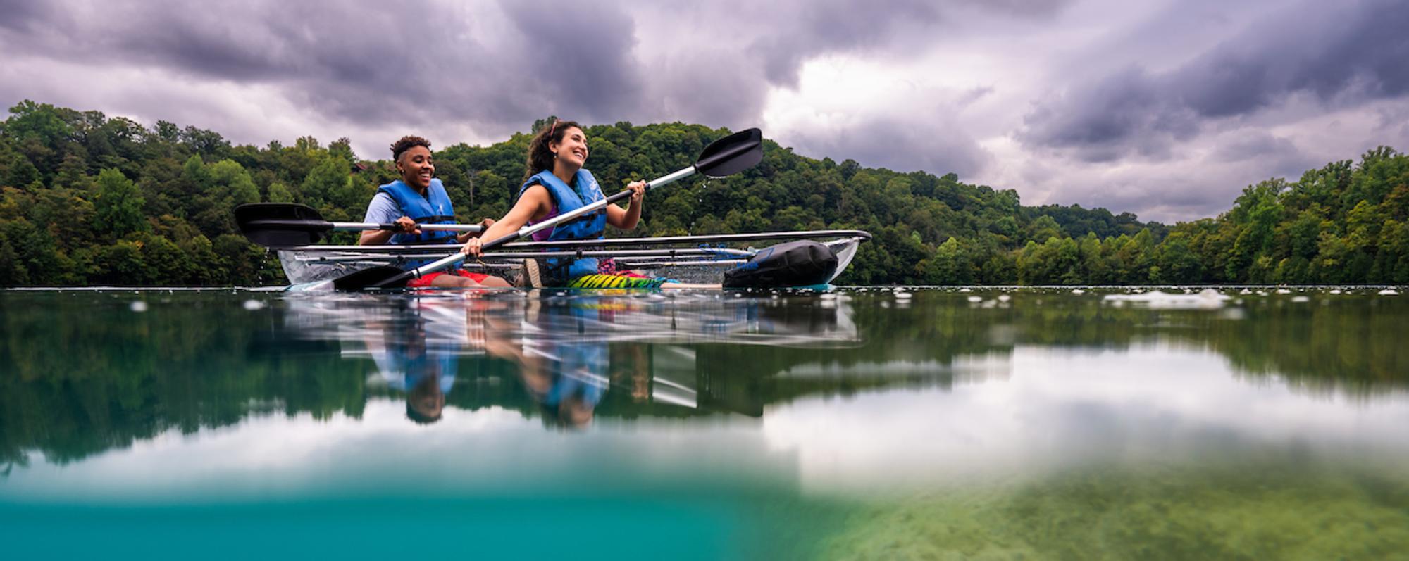 Two people kayaking in crystal kayak on lake