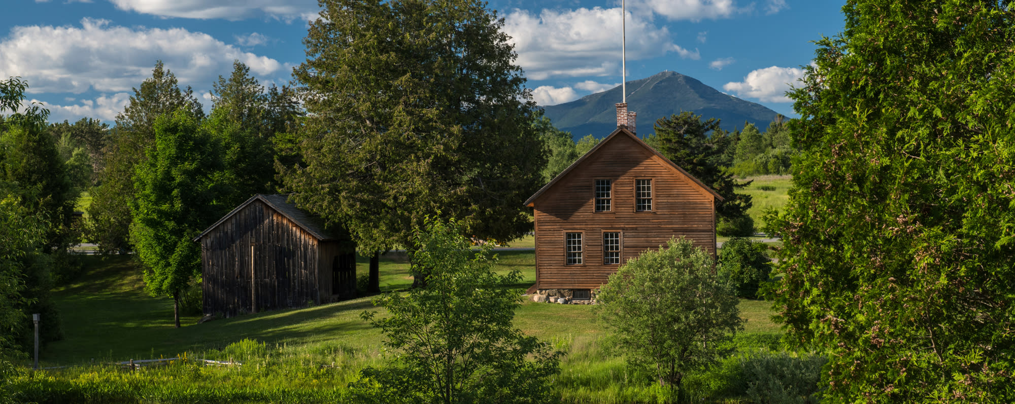 The green landscape and exterior of the John Brown Farm State Historic Site