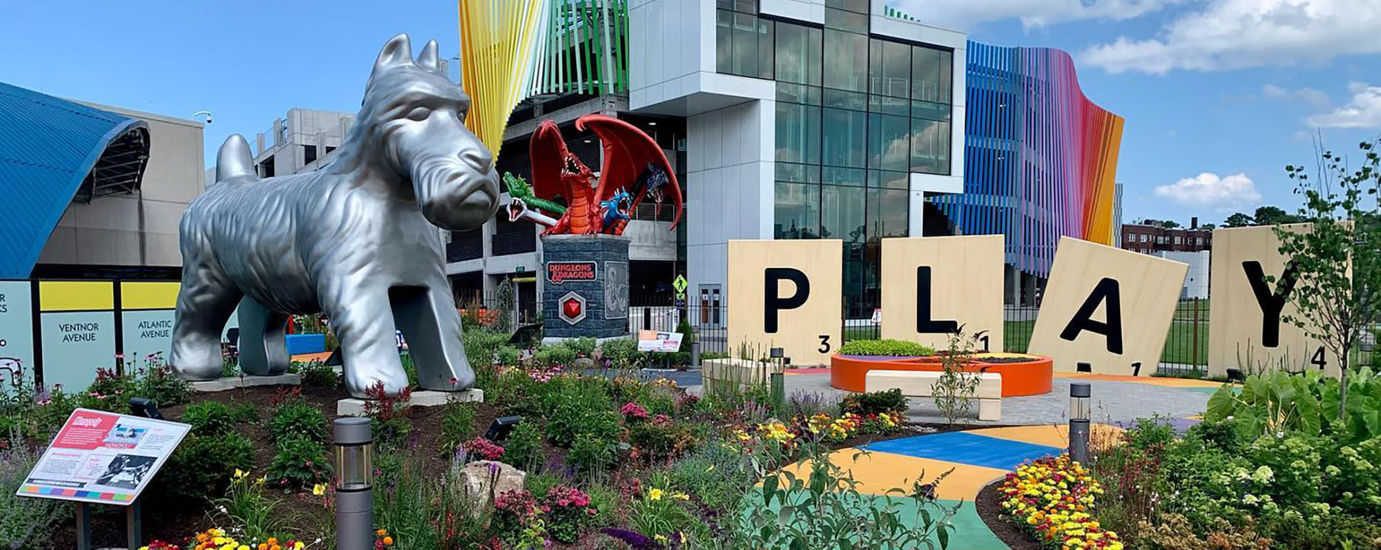 A giant Monopoly dog and Scrabble tile pieces spelling out the word "Play" stand in the winding Hasbro Game Park at the Strong National Museum of Play