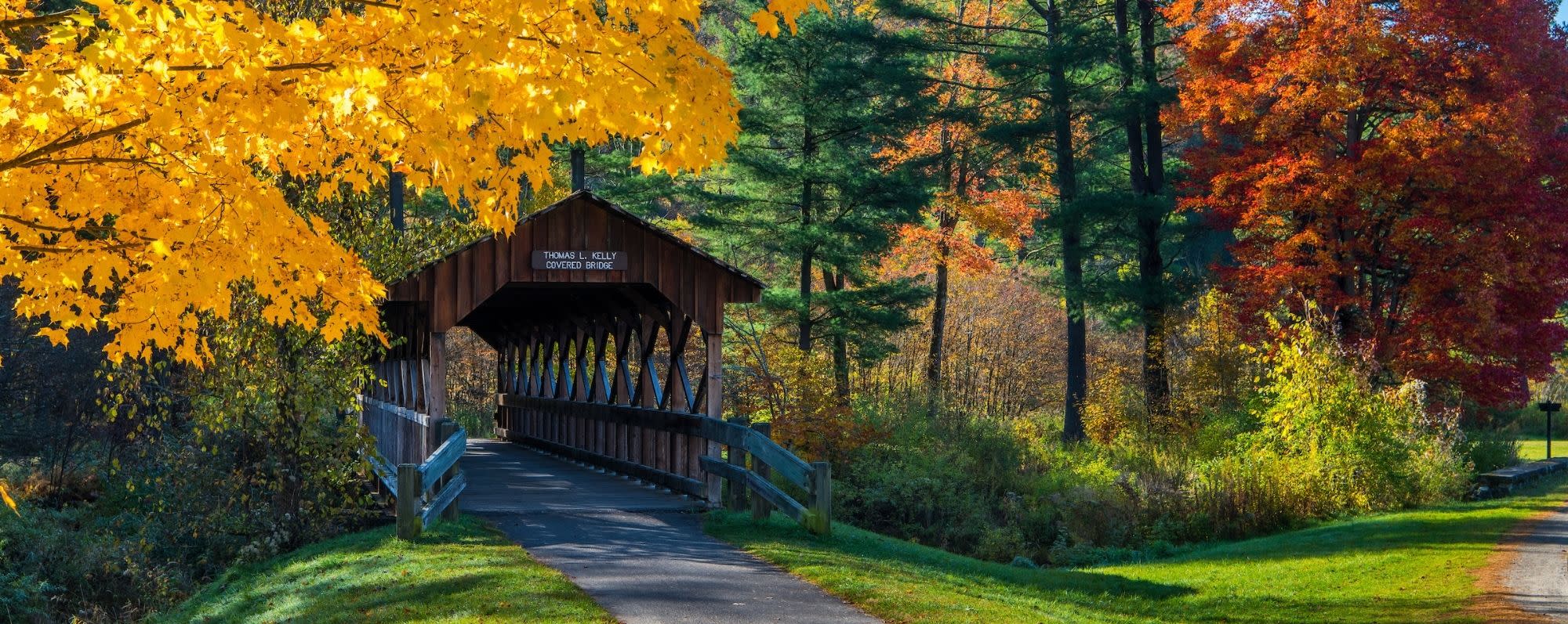 The Thomas L. Kelly Covered Bridge surrounded by fall foliage colors of yellow, green and orange