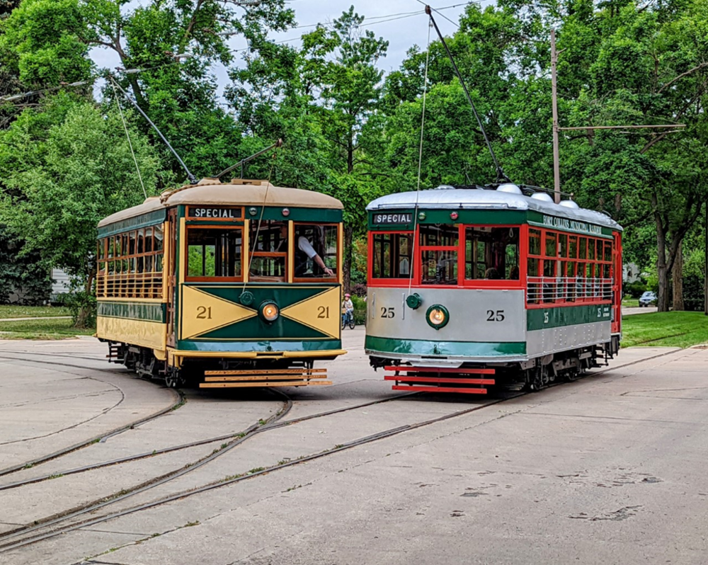 two trolley cars next to each other on the tracks
