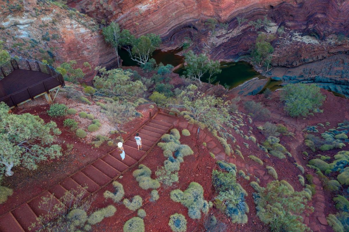 A couple walking down steps leading into Hamersley Gorge in Karijini National Park