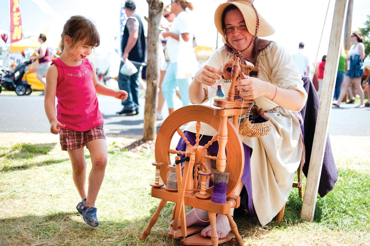 Little girl watching a woman spin yarn at the Kutztown Folk Festival