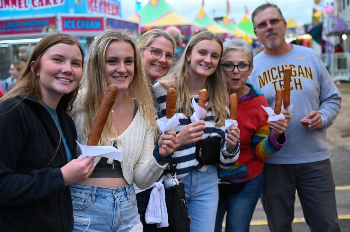A group of people holding up corndogs at the Northern WI State Fair