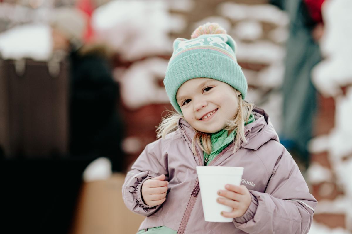 Girl smiles with cup of hot chocolate.