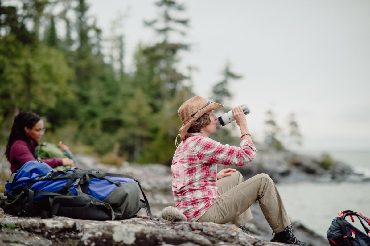 Woman takes a drink from reusable water bottle on Isle Royale