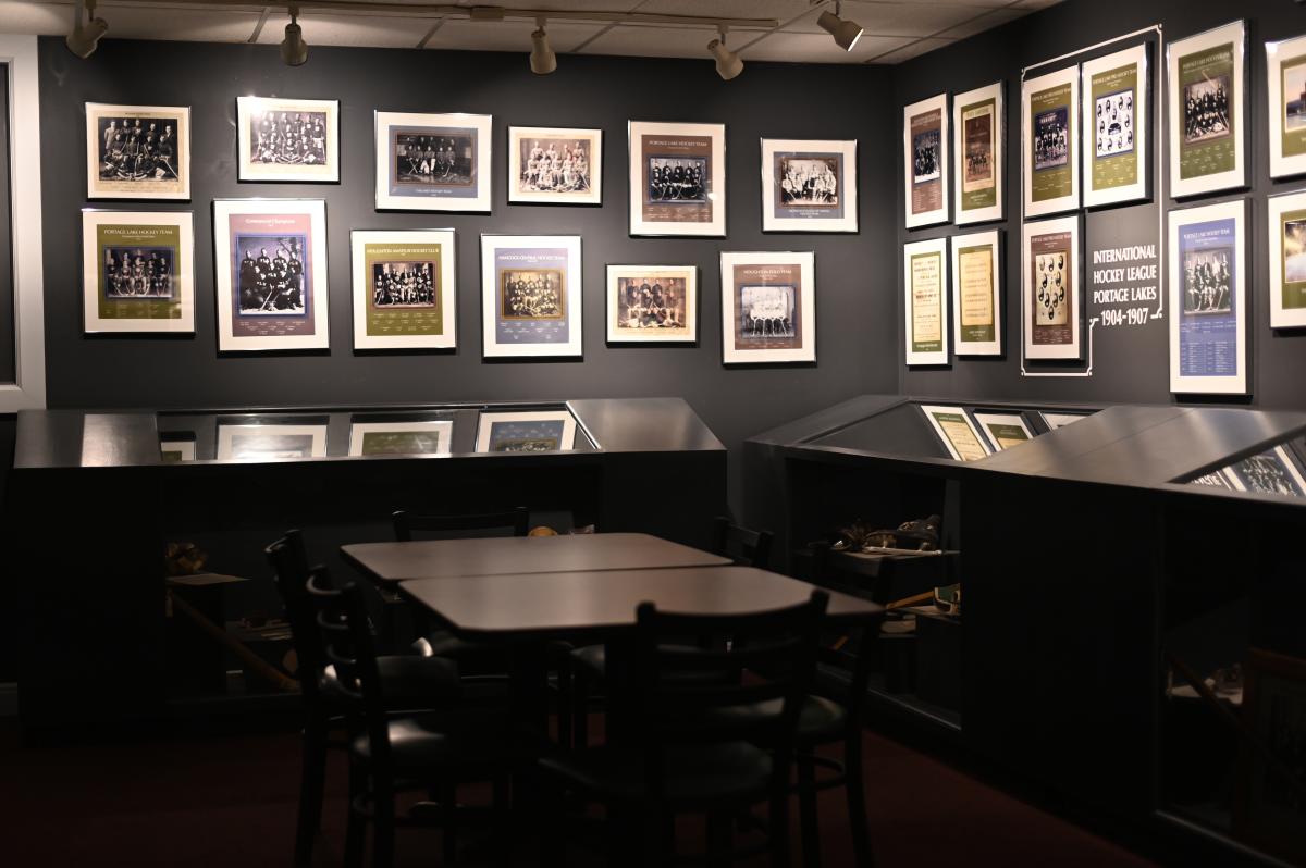 a dimly lit museum space with photos lining the walls