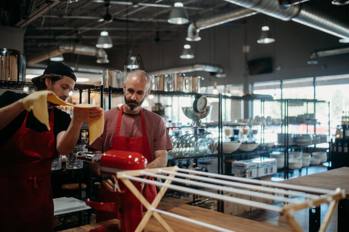 Two people making pasta together during a cooking class at The Local Epicurean.