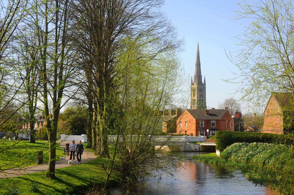 Man and woman walk their dog along the river side with church in background