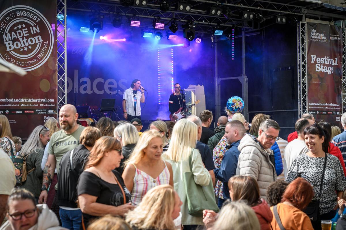 Band on stage in front of crowd in the sun at a festival